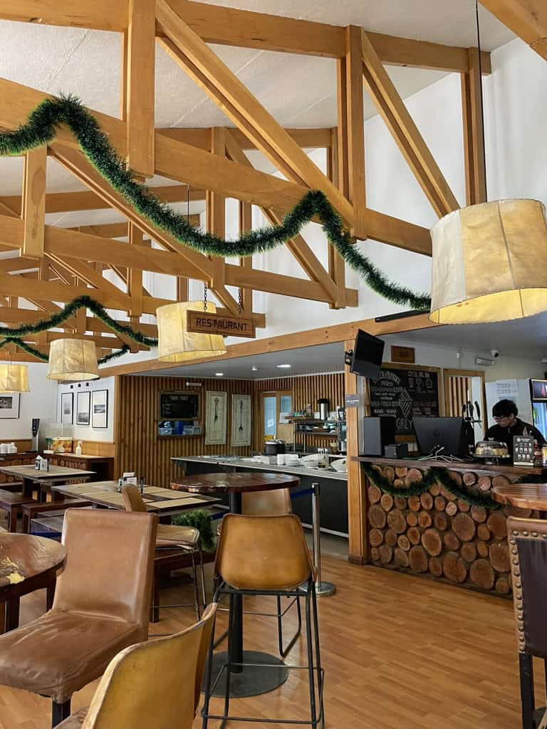 inside a lodge with wooden beams, white walls and tan coloured furniture