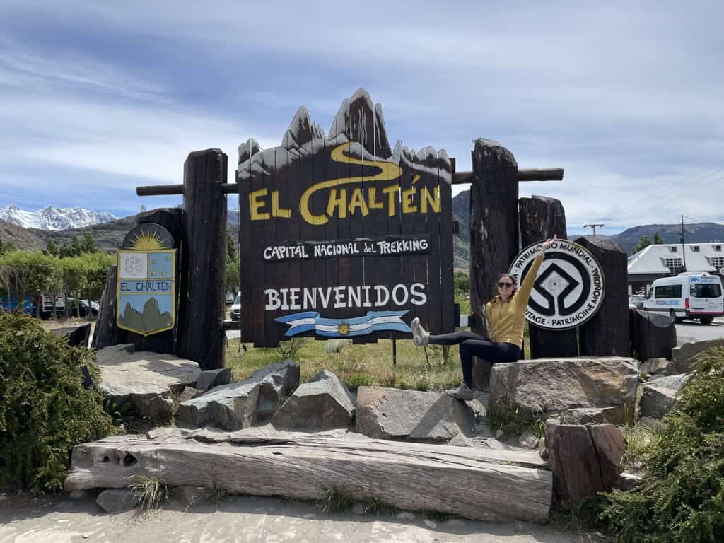 picture of female in yellow sweater infront of a wooden sign that says El Chalten while on a two week trip in Patagonia