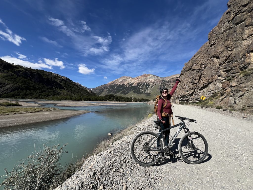 Girl in red shirt with bicycle on gravel road over looking Rio electrico streams and mountains