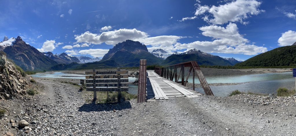 landscape shot of rio electrico with surronding mountains, wooden bridge and icy blue winding streams