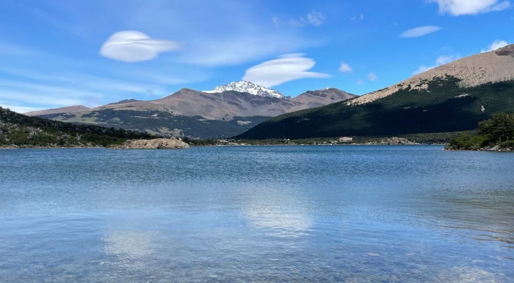 View of Laguna Capri in El Chalten with blue water and grey mountain landscape in the background